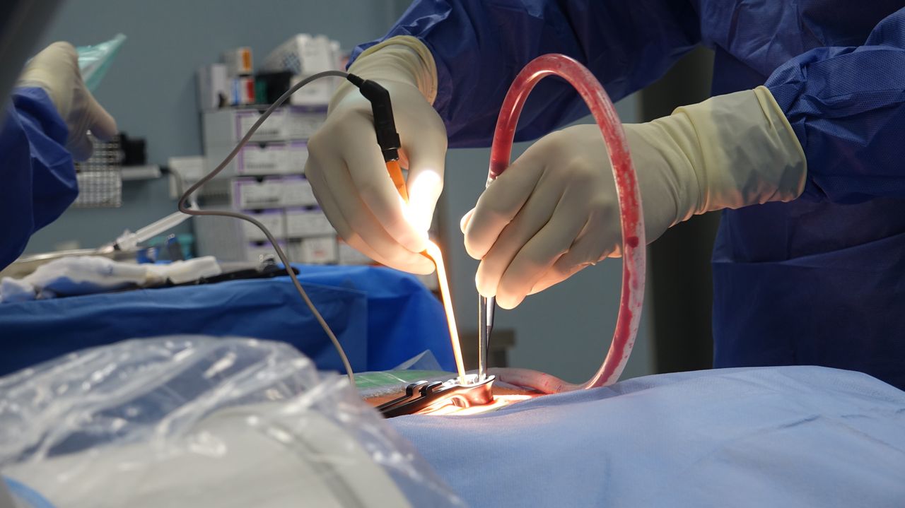 Medical professionals performing surgery in a sterile operating room setting.